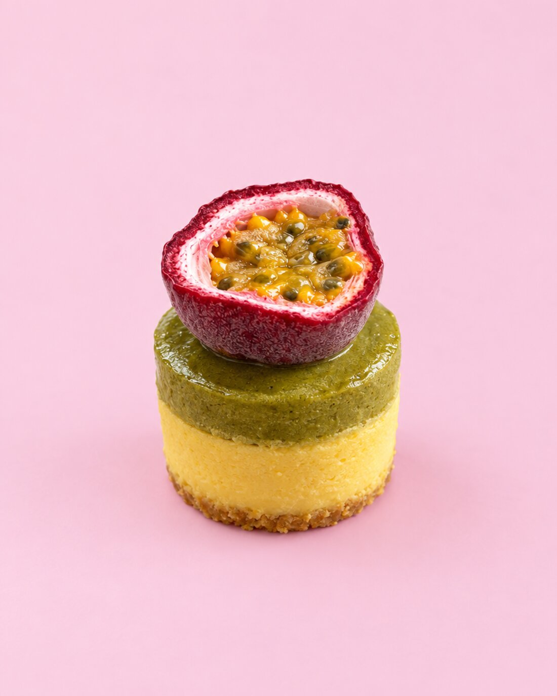 Runder zweischichtiger Mini-Cheesecake mit grüner Glasur und Maracuja